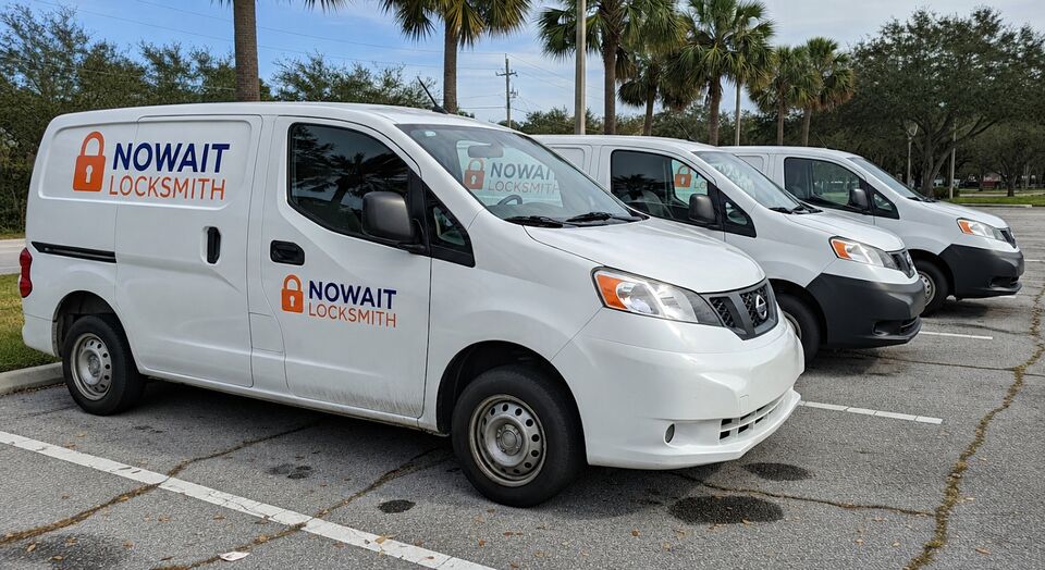Three white NoWait Locksmith vans parked in a row